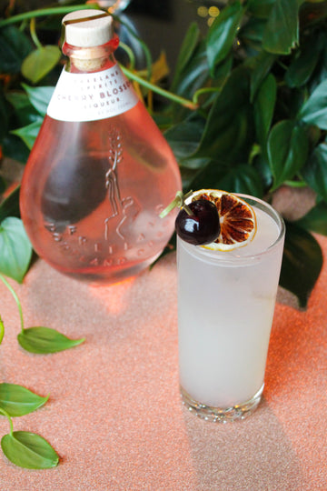 Bottle of Freeland Spirits Cherry Blossom Liqueur and a Cherry Blossom Collins Spring cocktail