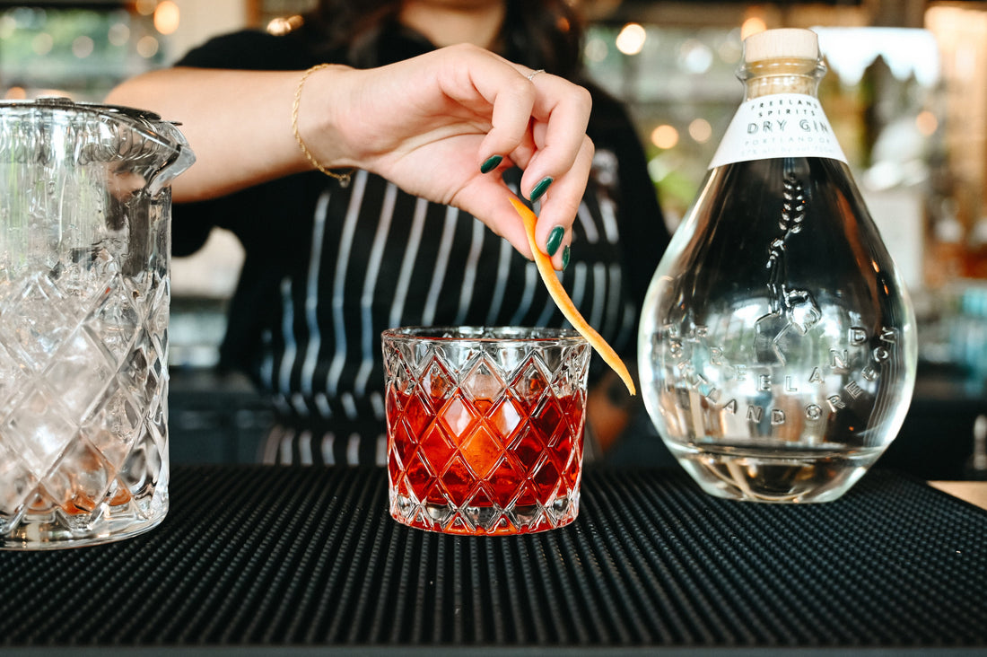 Mixologist at Freeland Spirits tasting room serving a Negroni next to a bottle of Freeland Dry Gin.