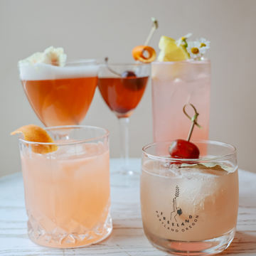 Group of cocktails in honor of Women's History Month. Each inspired by a flower, garnished with buds and fruits. 