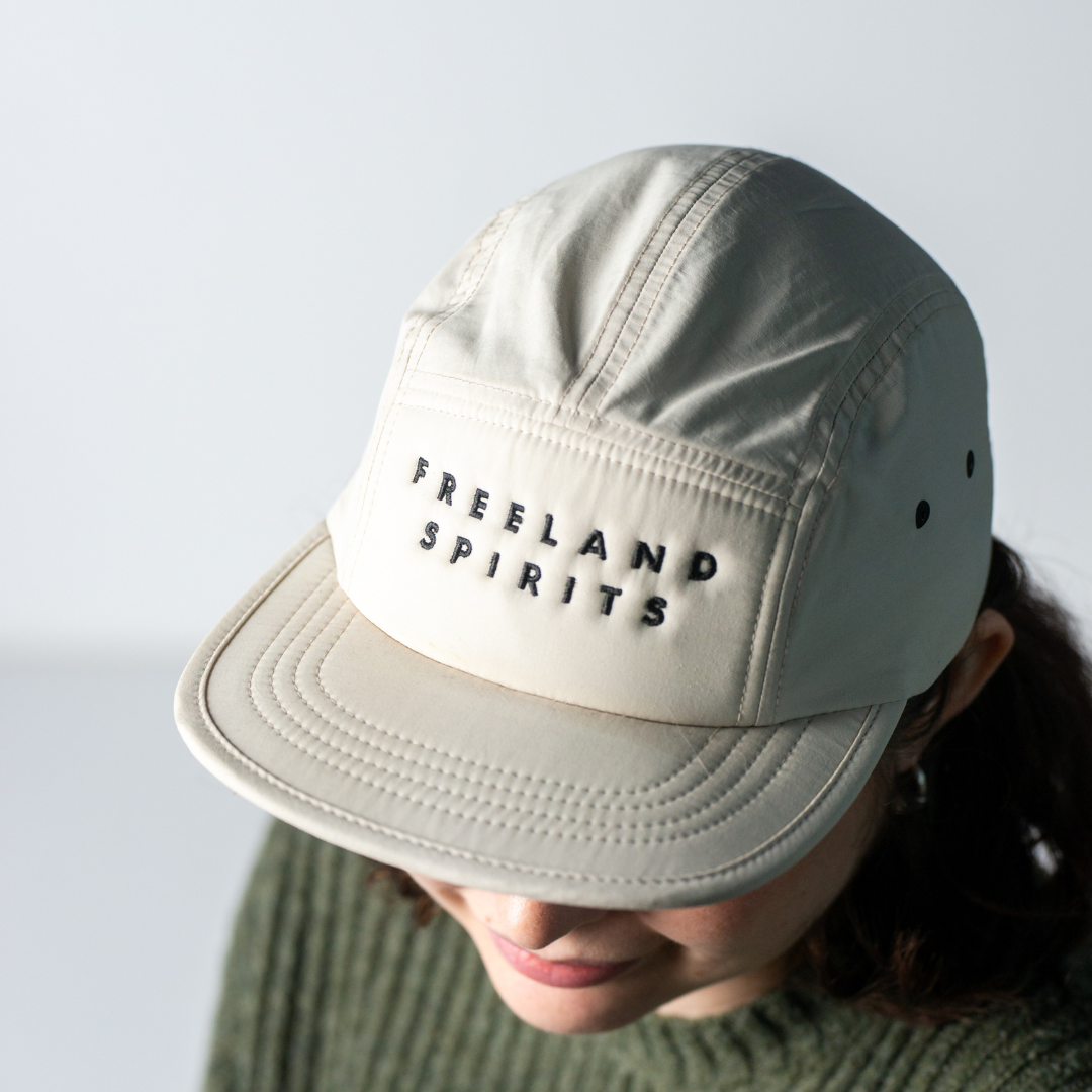 Model wearing Freeland Spirits Five-Panel Hat, white hat with black embroidered Freeland Spirits logo