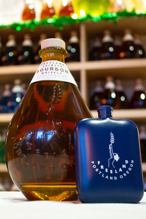 Freeland Spirits branded flask barware next to bottle of Freeland Bourbon