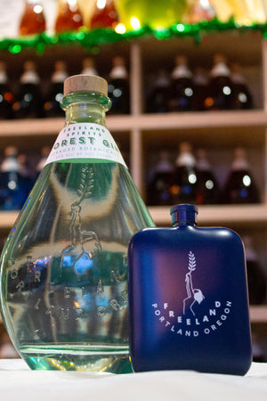 Freeland Spirits branded flask barware next to bottle of Freeland Forest Gin