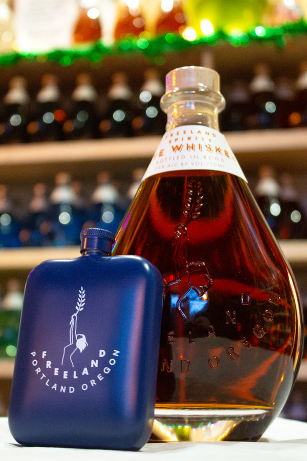 Freeland Spirits branded flask barware next to bottle of Freeland Rye Whiskey