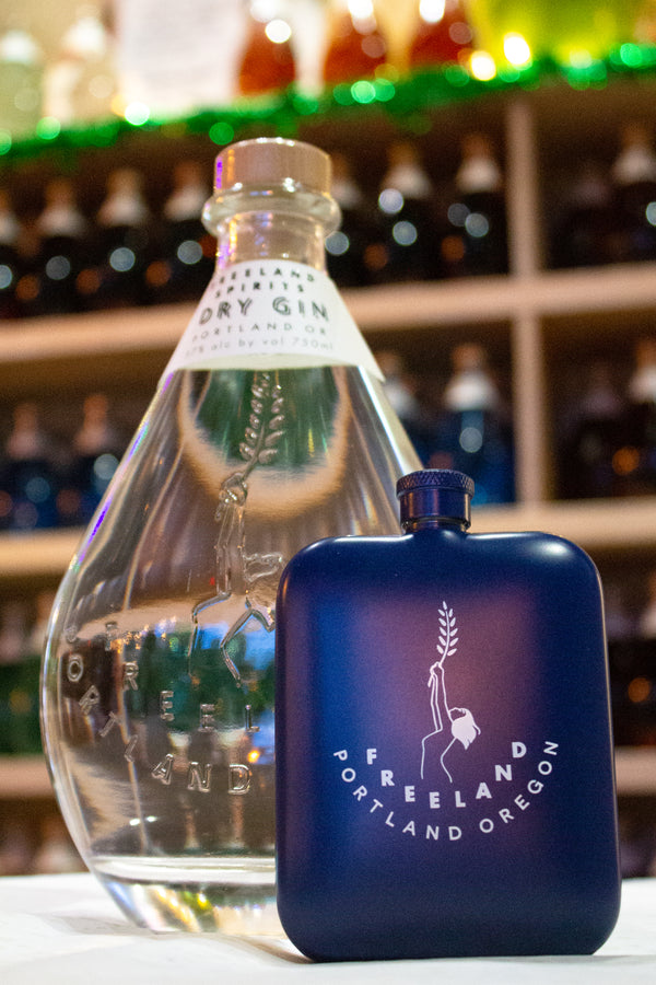 Freeland Spirits branded flask barware next to bottle of Freeland Dry Gin