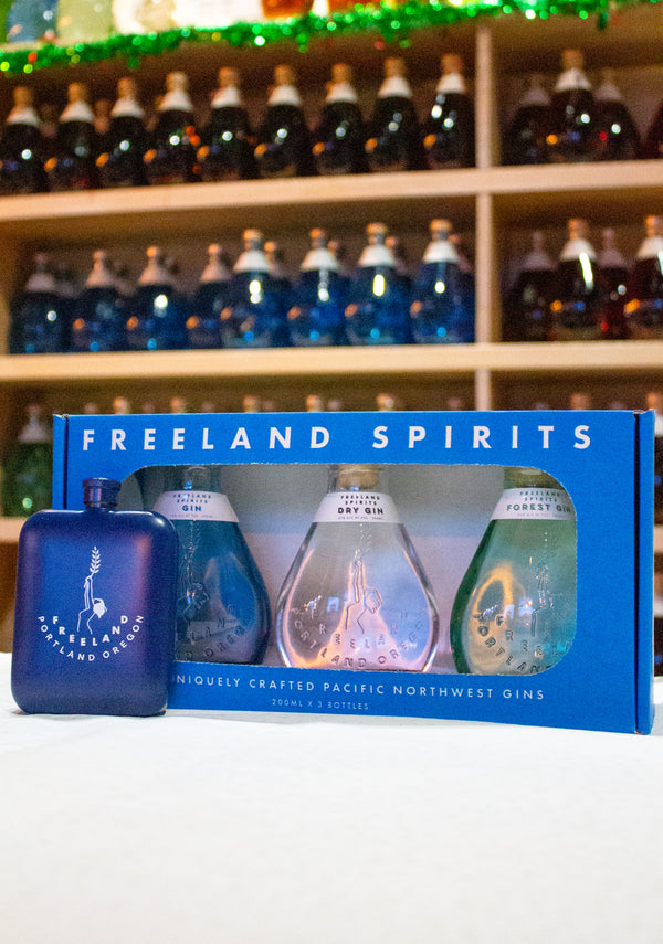 Freeland Spirits branded flask barware next to bottle of Freeland Gin Minis 3-Pack Holiday Gift Set