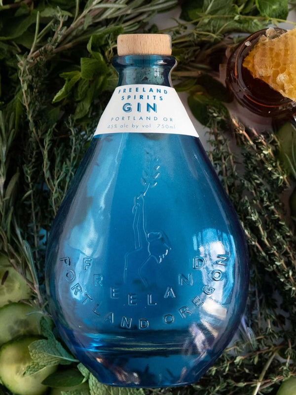 Freeland Spirits blue bottle Gin nestled in botanicals. Distilled in Portland, Oregon. 